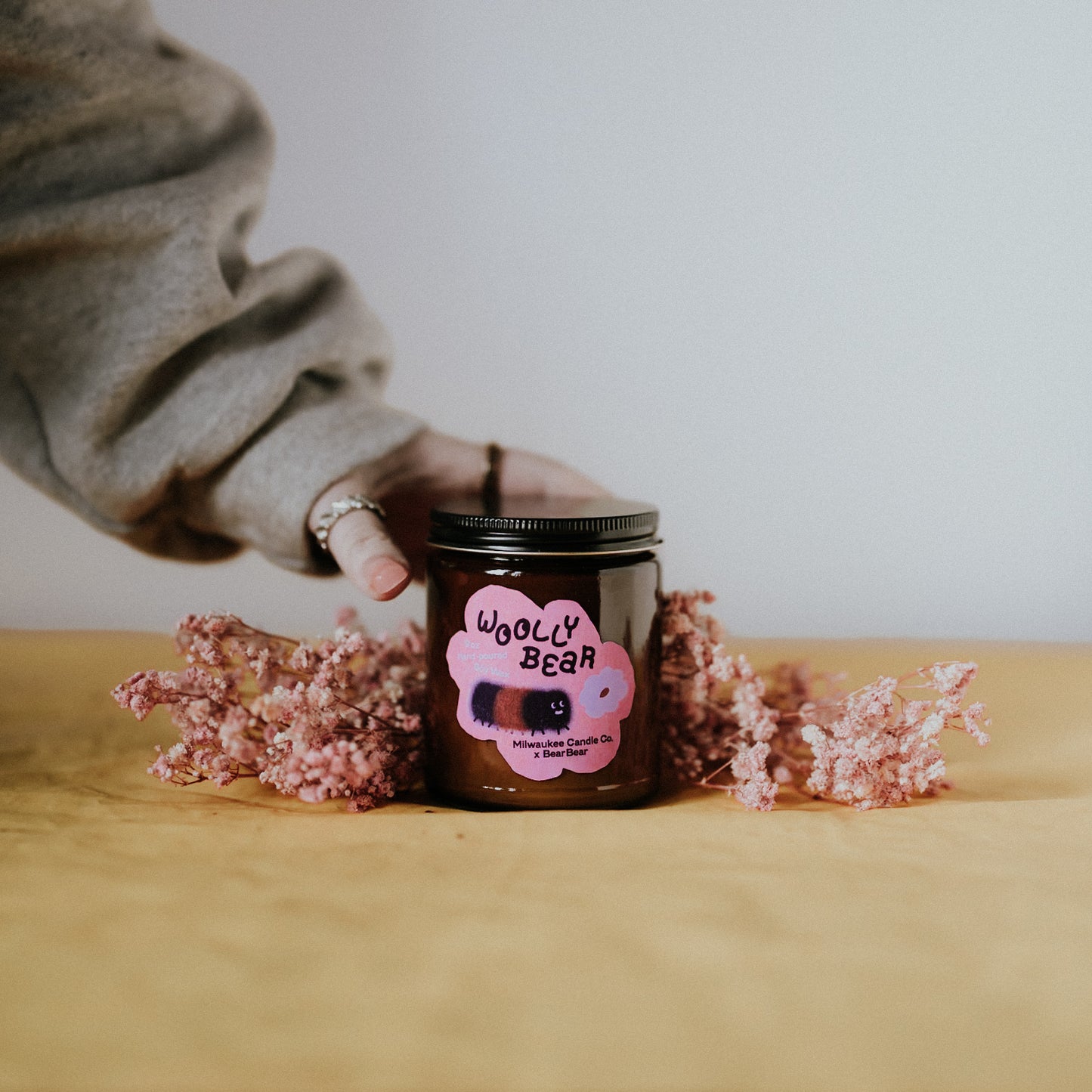 Hand Reaching for Woolly Bear Candle