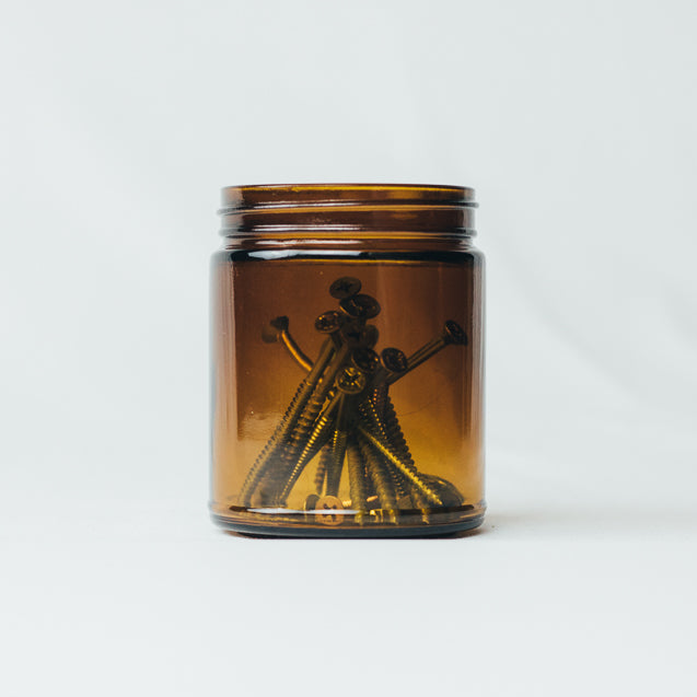 Cleaned and reused glassware holding a bunch of screws to support sustainability.