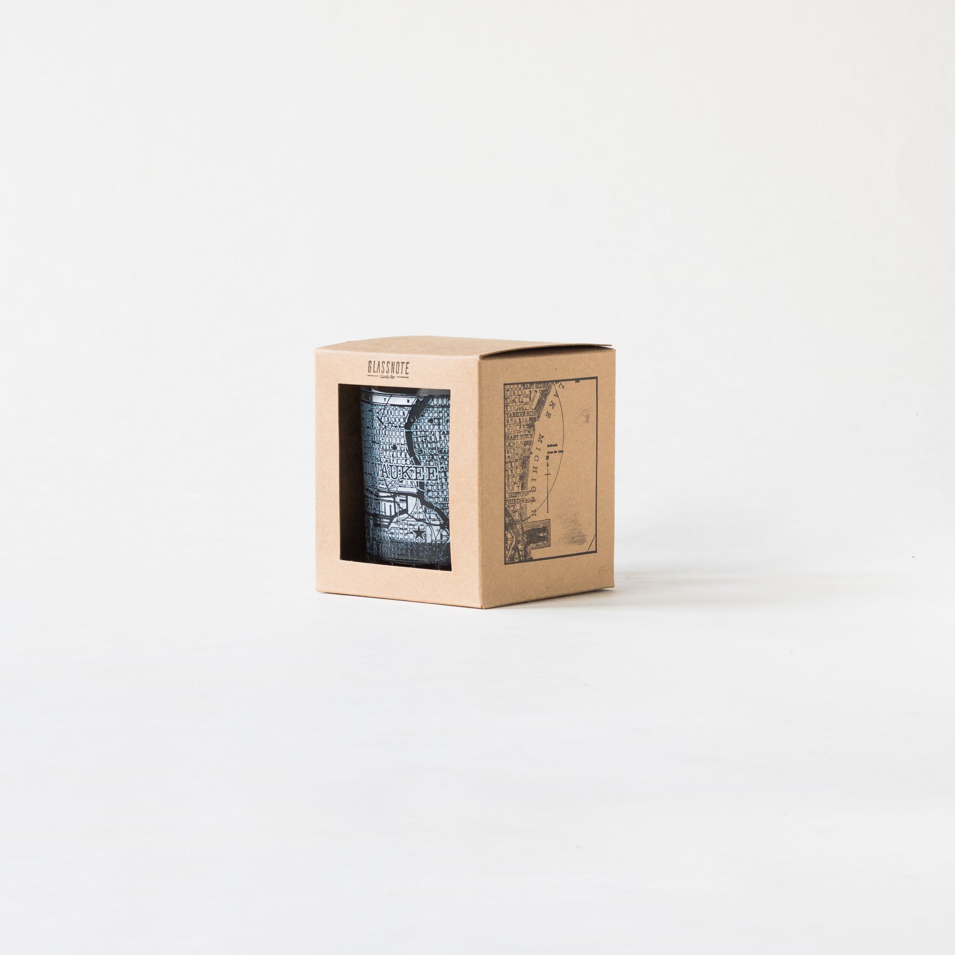 11oz whiskey rocks glass with a screen printed vintage map of Milwaukee. A Milwaukee Candle Co. and Glassnote Candle Bar collaboration. Front view of packaging (kraft box with square cutout, Glassnote logo stamped on the top center and map stamped onto the side)