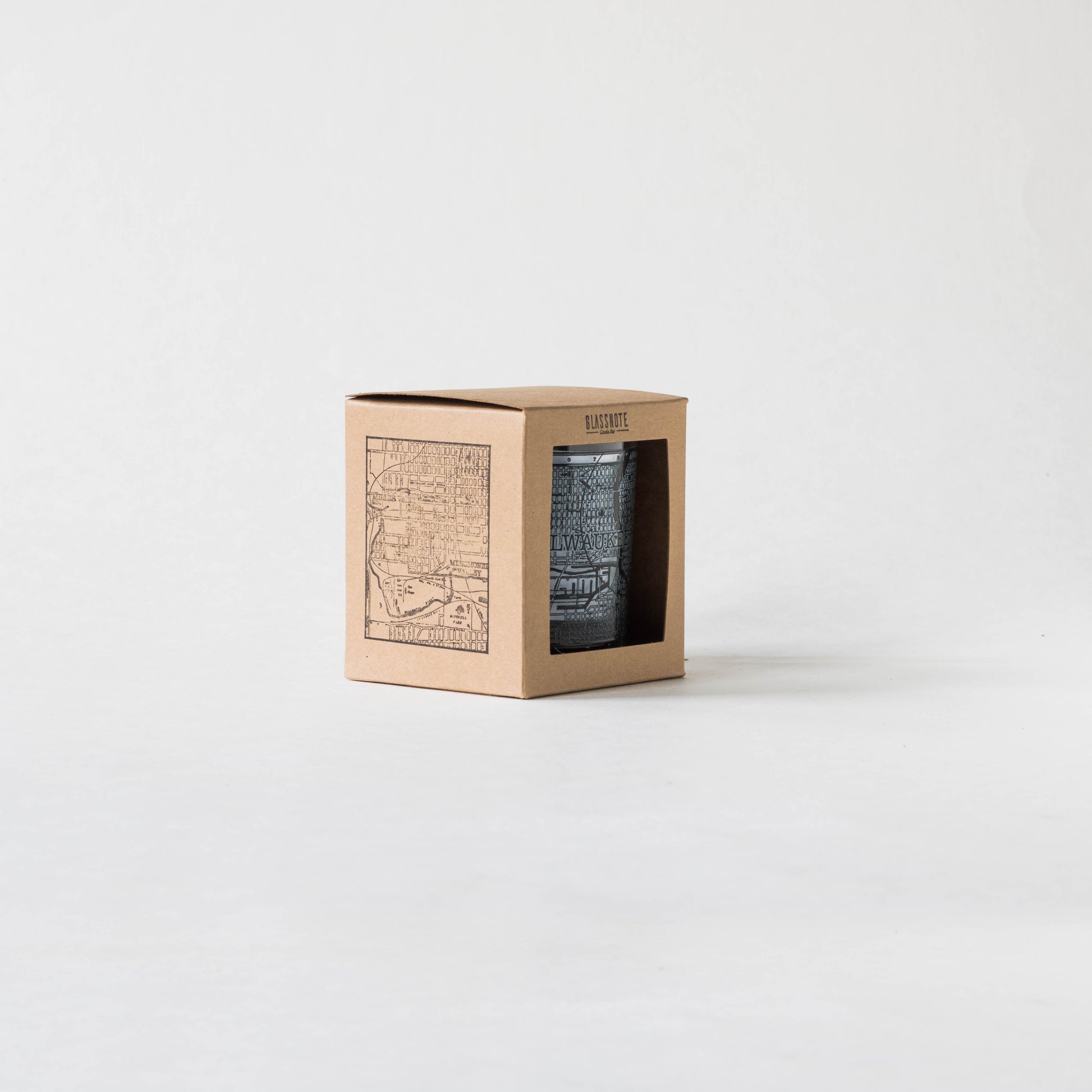 11oz whiskey rocks glass with a screen printed vintage map of Milwaukee. A Milwaukee Candle Co. and Glassnote Candle Bar collaboration. Front view of packaging (kraft box with square cutout, Glassnote logo stamped on the top center and map stamped onto the side)
