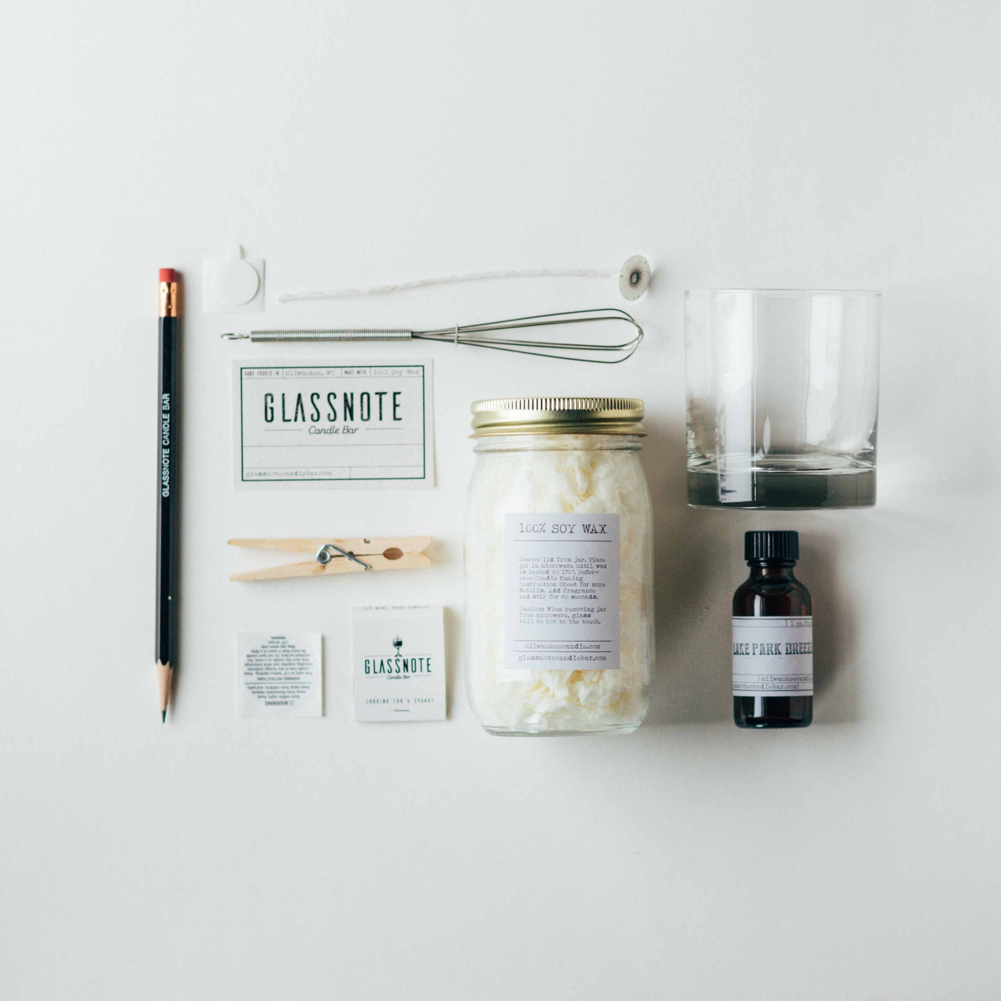 DIY candle making kit contents: pencil, wick, wick stickum, whisk, glass, soy wax jar, fragrance oil vial, label, clothespin, caution sticker, match box