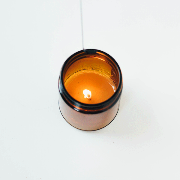 Black wick dipper extinguishing burning candle flame.