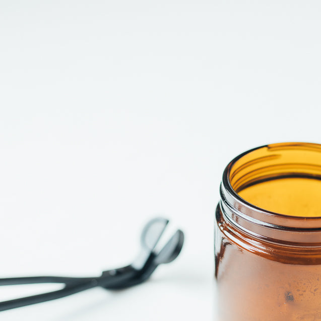 Wick trimmer and amber jar candle.