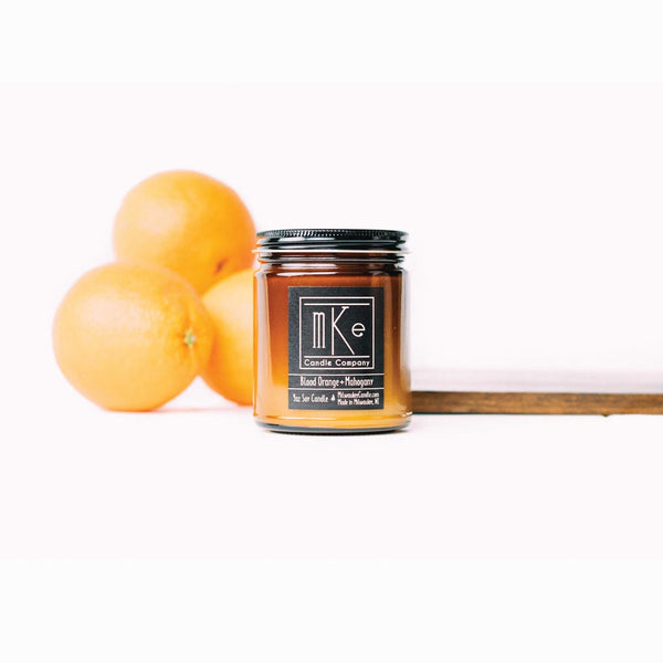 Blood Orange and Mahogany amber jar 9 ounce soy candle with oranges and plank of wood in background