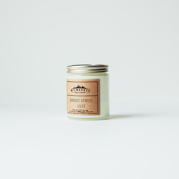 6 ounce Brady Street Daze clear jar soy wax candle with kraft paper label and gold lid. Hand-poured in Milwaukee, Wisconsin.