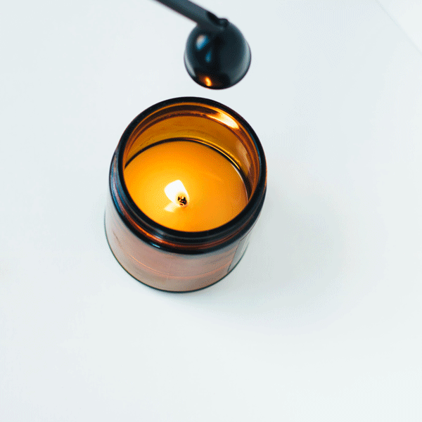 Black candle snuffer extinguishing burning flame.